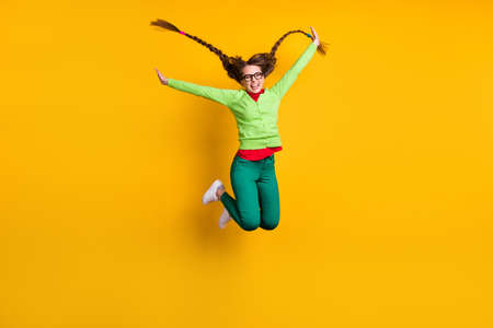 Full length body size view of attractive funky ecstatic cheerful girl jumping having fun isolated over bright yellow color backgroundの写真素材