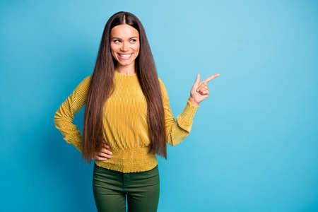 Photo portrait of girl pointing finger at blank space isolated on pastel blue colored background