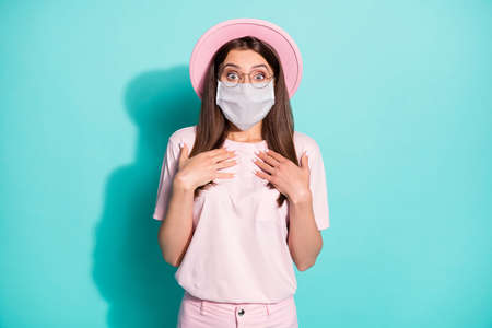 Photo of astonished young girl point hands on herself wear medical safe mask isolated over turquoise color backgroundの写真素材