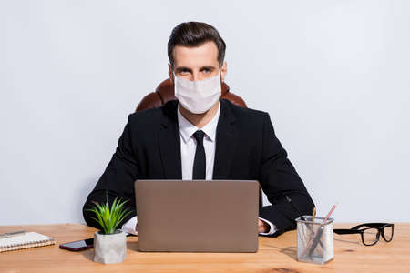 Photo of business man sitting in armchair on workplace wearing face mask isolated grey backgroundの写真素材