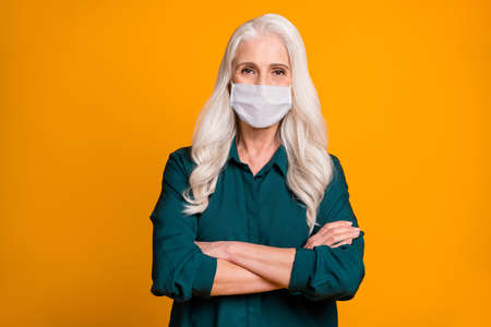 Photo of grandma with hands crossed wear white face mask isolated bright yellow color background