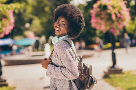 Back rear spine view photo of attractive charming afro american girl walk in outside summer town parkの写真素材