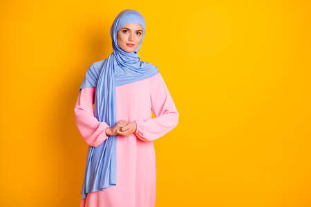Portrait of attractive fashionable peaceful modest muslimah wearing cosy dress isolated over bright...