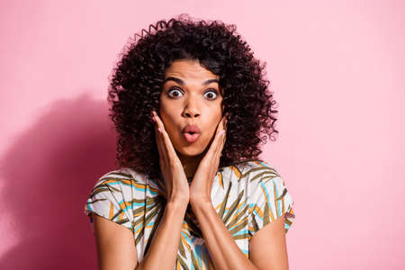 Photo portrait of shocked woman touching face with two hands isolated on pastel pink colored backgroundの写真素材