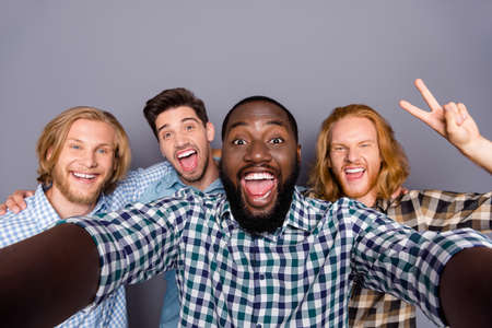 Self-portrait of four nice attractive funky cheerful cheery positive guys embracing having fun meeting classmates showing v-sign fooling isolated over gray purple pastel color backgroundの写真素材