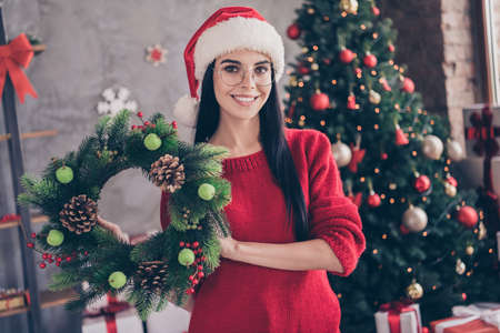 Photo of girl wear santa claus hat hold christmas wreath in house indoors with x-mas garlands decor