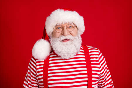 Photo of pensioner old man cheerful smiling prepare sledge deer presents work christmas holiday wear santa costume suspenders spectacles striped shirt headwear isolated red color backgroundの写真素材