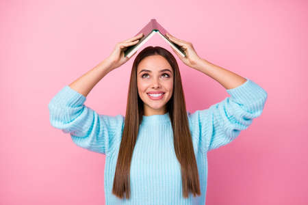 Photo of attractive funny lady hold book hands above head spend free time hobby tricky behavior mood...