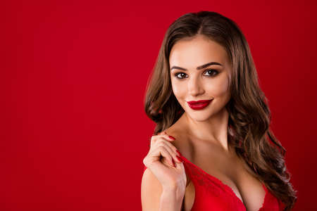 Photo portrait of flirty woman taking off bra isolated on vivid red colored background with blank...