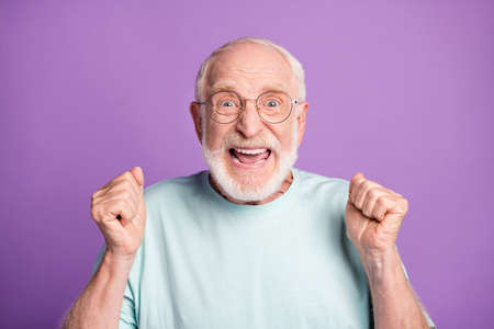 Portrait of celebrate happy pensioner hands fists yell wear casual cloth isolated on violet color backgroundの写真素材