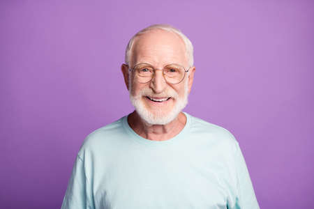 Portrait of smiling optimistic beard pensioner man wear light blue t-shirt eyeglasses isolated on...