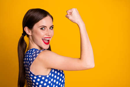Close-up profile side view portrait of her she nice attractive pretty strong lucky successful cheerful cheery girl showing muscles yes win isolated bright vivid shine vibrant yellow color backgroundの写真素材