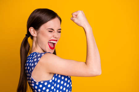 Close-up profile side view portrait of her she nice attractive overjoyed crazy successful cheerful cheery girl showing muscles celebrating isolated bright vivid shine vibrant yellow color backgroundの写真素材