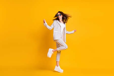 Full length body size side profile photo of girl wearing checkered suit round sunglass dancing laughing isolated on bright color backgroundの写真素材