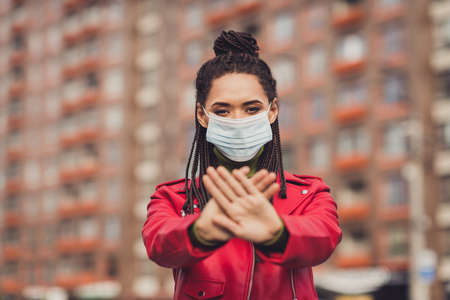 Photo of young african woman wear protection medical mask quarantine crossed hands stop coronavirus covid-19 streetの写真素材