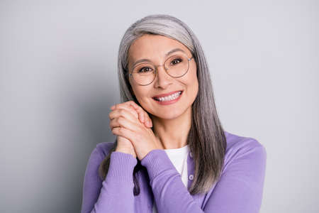 Photo portrait of granny glad to see her grandchildren holding two hands near face wearing violet shirt isolated on grey colored background