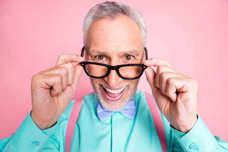 Closeup headshot photo of happy funny old man touching eyeglasses smiling laughing isolated on pink...