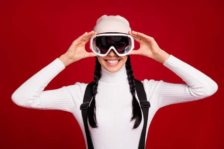 Photo of young happy positive smiling girl wear goggles celebrate new year in resort isolated on red...
