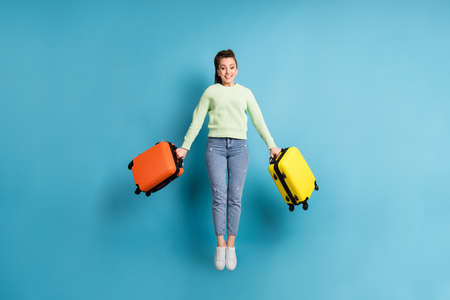 Full length body size photo of jumping girl keeping colorful suitcases before flight in airport...