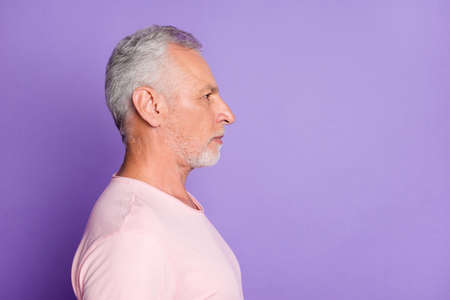 Profile photo of retired old man calm expression look empty space wear pink t-shirt isolated violet color backgroundの写真素材