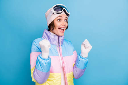 Photo of pretty lucky girl raise fists look copyspace wear white gloves hat winter vacation isolated on blue color backgroundの写真素材