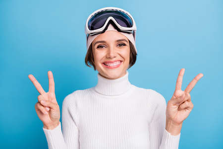 Photo of positive attractive woman show two v-sign greeting symbol skier isolated on pastel blue color backgroundの写真素材