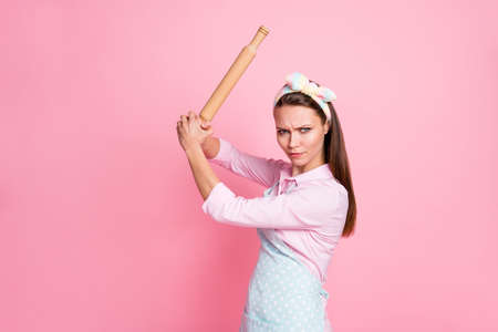 Portrait of her she nice attractive dangerous mad serious housewife holding in hands rolling pin threatening fighting rights gender equality isolated over pink pastel color backgroundの写真素材
