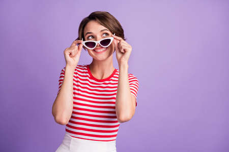 Photo of young girl take off specs look up empty space wear sunglass striped t-shirt isolated violet...