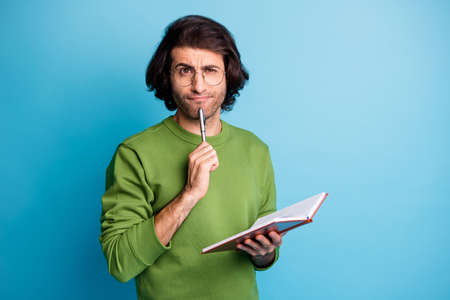 Photo of minded guy hold notebook pen chin think wear eyewear green sweater isolated blue color...