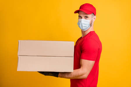 Profile photo of delivery man hold two big packages wear mask red t-shirt cap isolated yellow color...