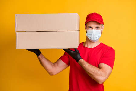 Photo of delivery guy hold demonstrate two big boxes wear gloves mask red t-shirt hat isolated...