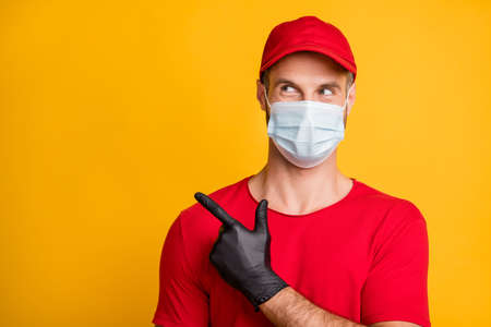 Photo of interested man indicate forefinger look empty space wear mask red t-shirt hat isolated yellow color backgroundの写真素材