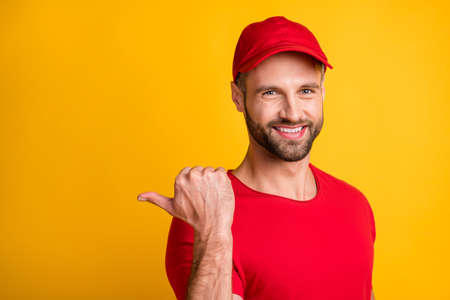 Photo of bristled man direct thumb back empty space wear red t-shirt cap isolated yellow color backgroundの写真素材