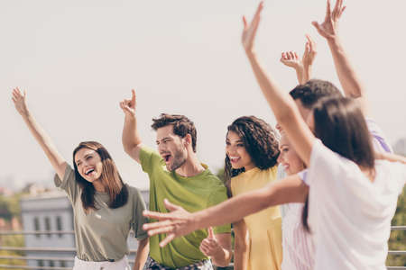 Portrait of company of friends cheerful raise hands up wear casual clothing partying roof restaurant outdoorsの写真素材