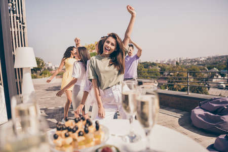 Photo of friendly pretty guys have fun dancing meals drinks on table party on roof terrace outsideの写真素材