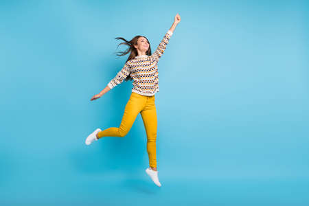 Full length photo of sweet woman dressed ornament pullover jumping empty space rising fist isolated...
