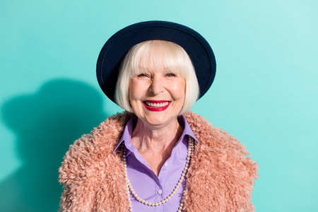 Photo of adorable cute senior lady wear retro jacket headwear smiling isolated teal color backgroundの写真素材