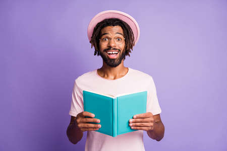 Photo of young african handsome smiling cheerful happy man male guy hold blue notebook isolated on purple color backgroundの写真素材