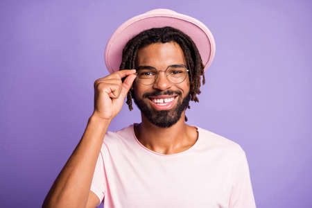 Photo portrait of man touching glasses with fingers isolated on vivid violet colored backgroundの写真素材
