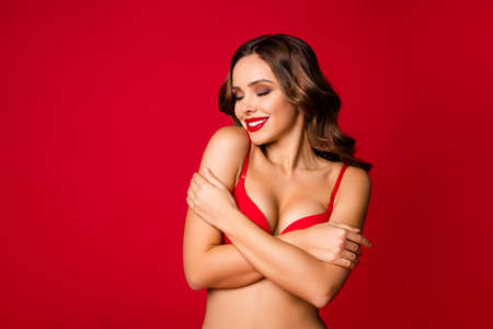 Close-up portrait of her she nice-looking attractive lovely glamorous stunning cheerful wavy-haired girl embracing herself isolated on bright vivid shine vibrant red color backgroundの写真素材