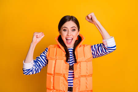 Portrait of ecstatic girl raise fists scream enjoy rescue tourist wear orange life guard vest isolated over bright shine color backgroundの写真素材