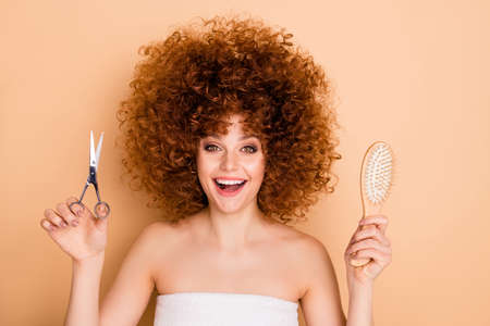 Close-up portrait of her she nice cute charming attractive cheerful wavy-haired girl model choosing solution between comb vs scissors pampering body bodycare isolated over beige pastel backgroundの写真素材