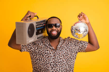 Photo of crazy funny cool dark skin guy hold retro tape recorder glitter disco ball rejoicing summer...