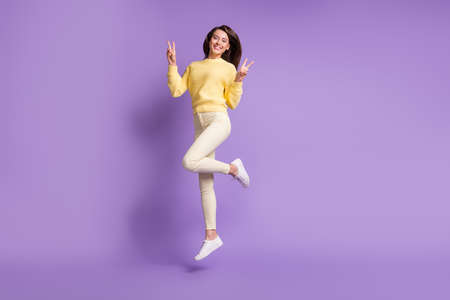 Full length photo portrait of girl jumping up showing two v-signs isolated on vivid violet colored...