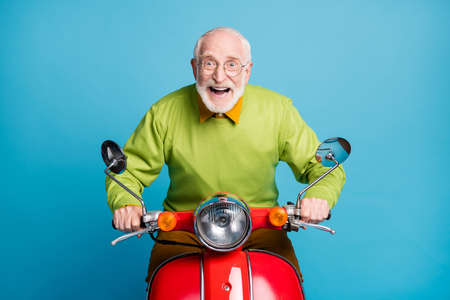 Photo of pensioner carefree grandpa ride motorcycle crazy expression wear eyeglasses green sweater isolated blue color backgroundの写真素材