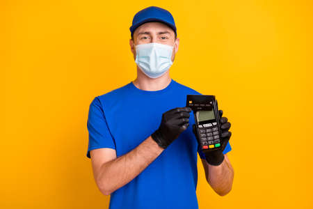 Photo of working person hold debit card terminal make purchase safety respiratory isolated on yellow...
