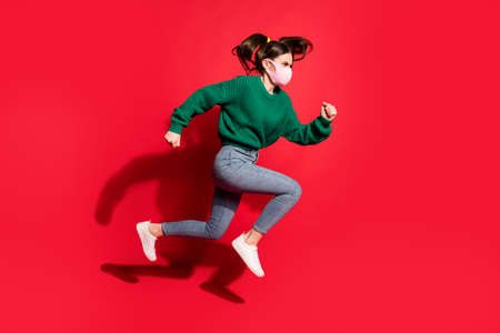 Profile side photo of trendy brunette tails girl jump run empty space wear jeans green jumper mask...