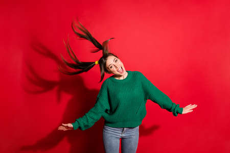 Photo of shiny sweet young lady wear green knitted pullover dancing isolated red color background