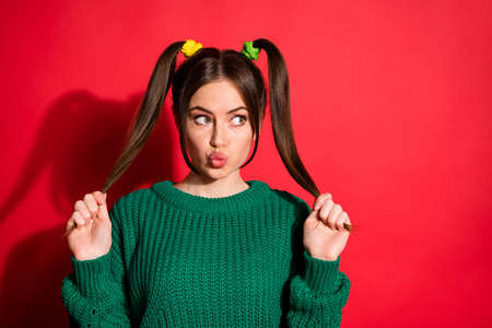 Portrait of pretty nice girl blow kiss hold tails look empty space dress green sweater isolated on red color backgroundの写真素材