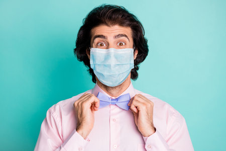 Photo of handsome cute boyfriend wear pink medical mask two arms fix bow tie isolated teal color backgroundの写真素材